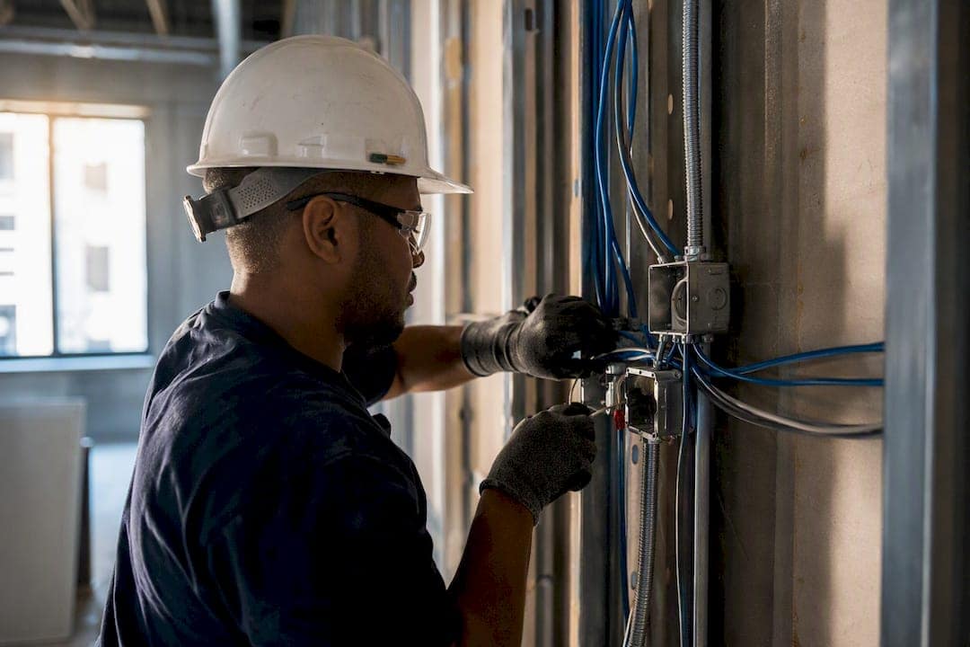 Electrician wiring conduit in commercial wall